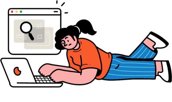 Une femme allongée à plat ventre devant son ordinateur fait un travail de recherche qui semble lui demander beaucoup d'efforts.